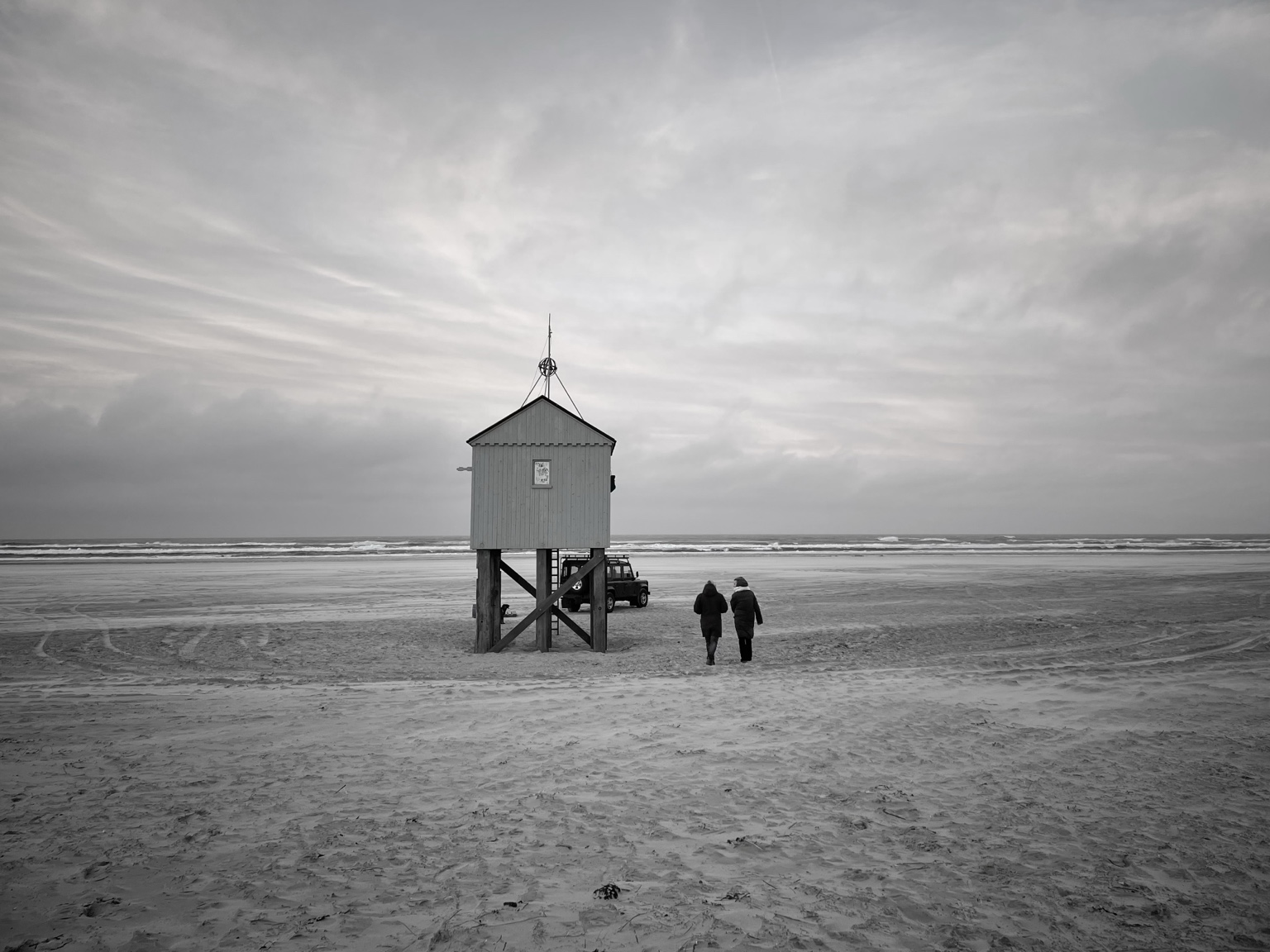 Pim en een ondernemer lopen op het strand langs het drenkelingenhuisje